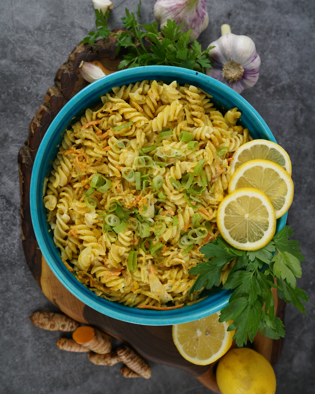 Einfacher Nudelsalat mit Mayo und Joghurt angerichtet in einer blauen Schüssel und Zitronenscheiben