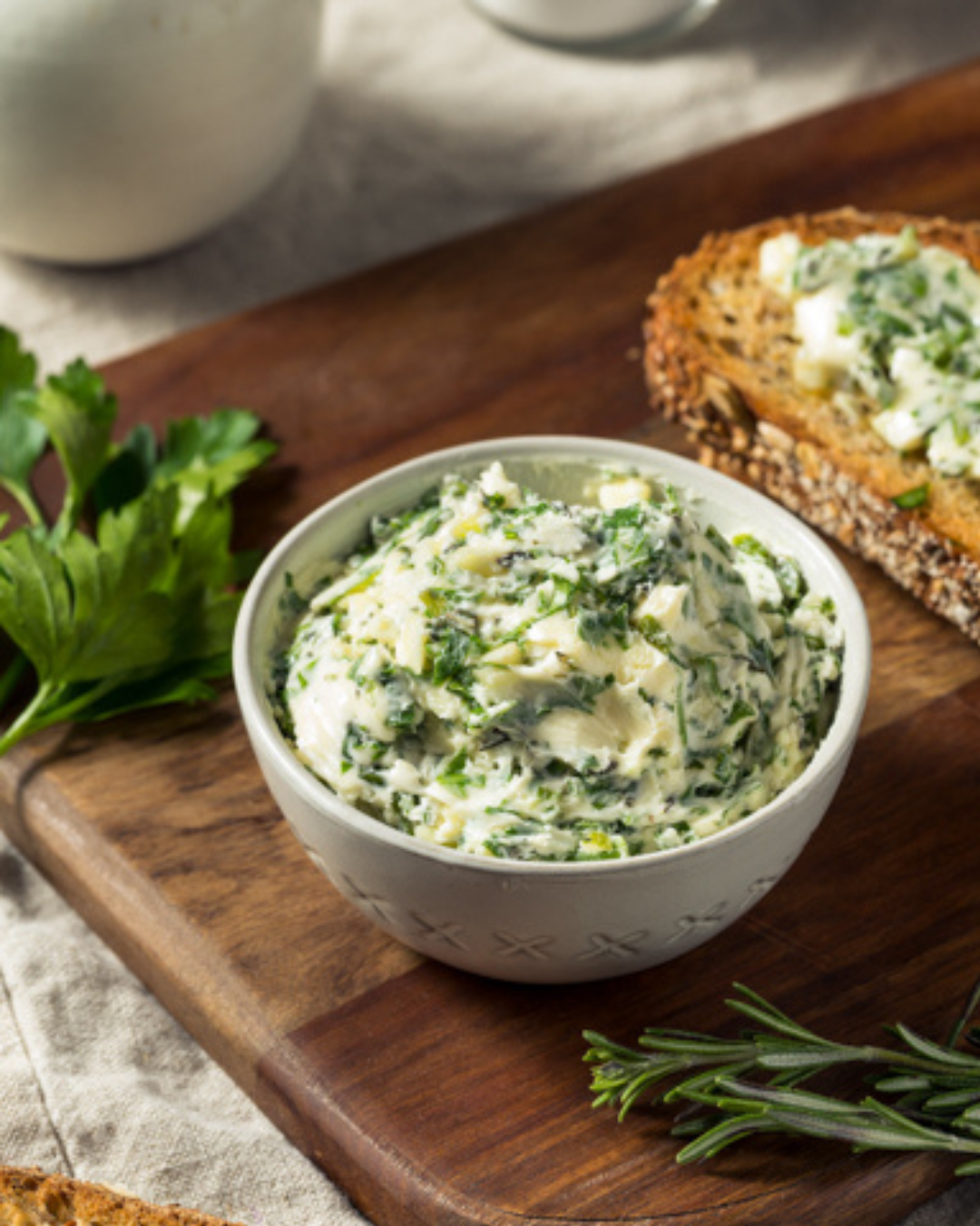 Knoblauchbutter Rezept selber machen in einer Dipschale dekoriert mit Brot und frischen Kräutern